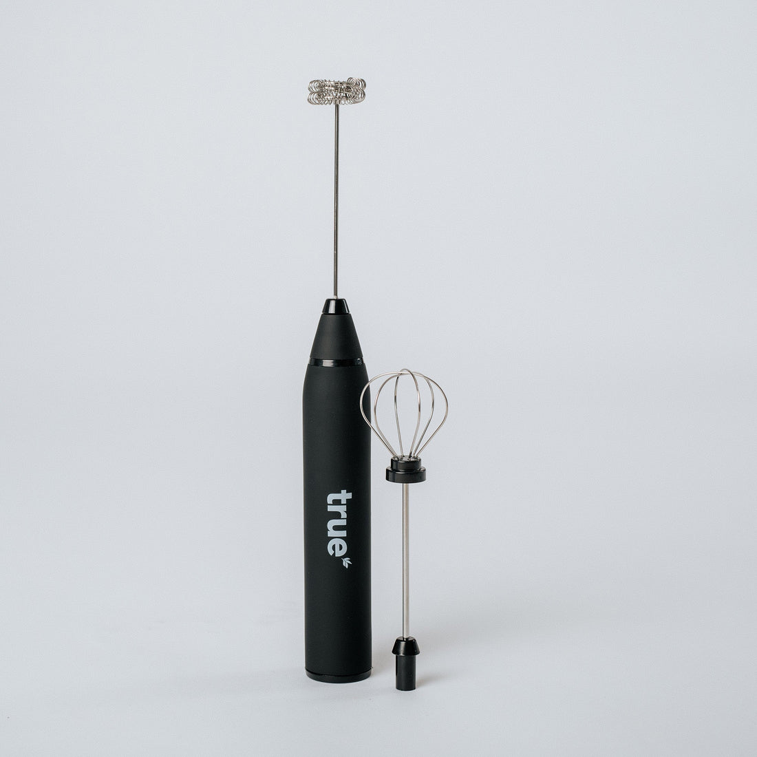 Black "True" handheld electric milk frother with detachable whisk and balloon attachment on white background — compact battery-powered hand mixer for coffee, lattes, cappuccinos, and home kitchens.