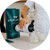 True plant protein probiotic powder bag with branded shaker bottle pouring protein shake into two glasses on a kitchen counter