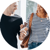 Young adults sharing a mobile referral link on a smartphone — friends using a referral program app for discounts and rewards